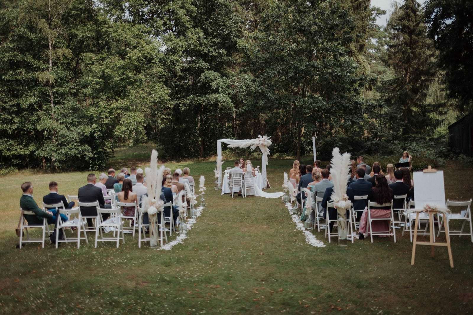Freie Trauung am Waldrand mit Pampasgras-Altar und weißen Stühlen, Hotel Waldhof auf Herrenland